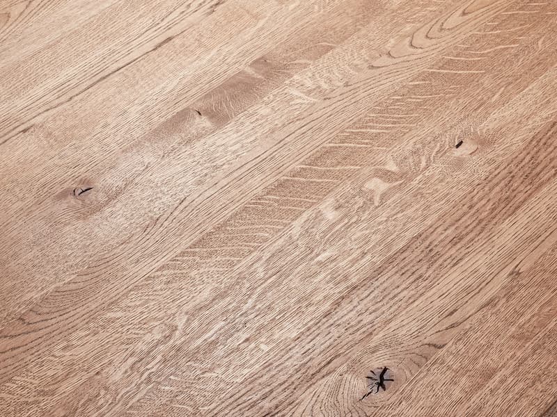 A wooden surface shows detailed grain patterns and natural imperfections, including knots and lines. The wood appears polished and smooth, covering the entire frame without any additional objects present.
